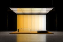 Modern retail storefront mockup with yellow gradient panels, sleek black bench, circular display platform, overhead lighting