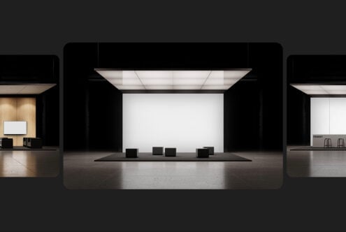 Modern trade show booth mockup with blank white wall, black cubes on stage, overhead lighting