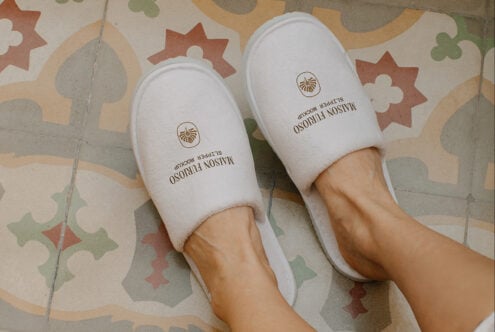 White slippers with shell logo on retro tile floor with geometric shapes