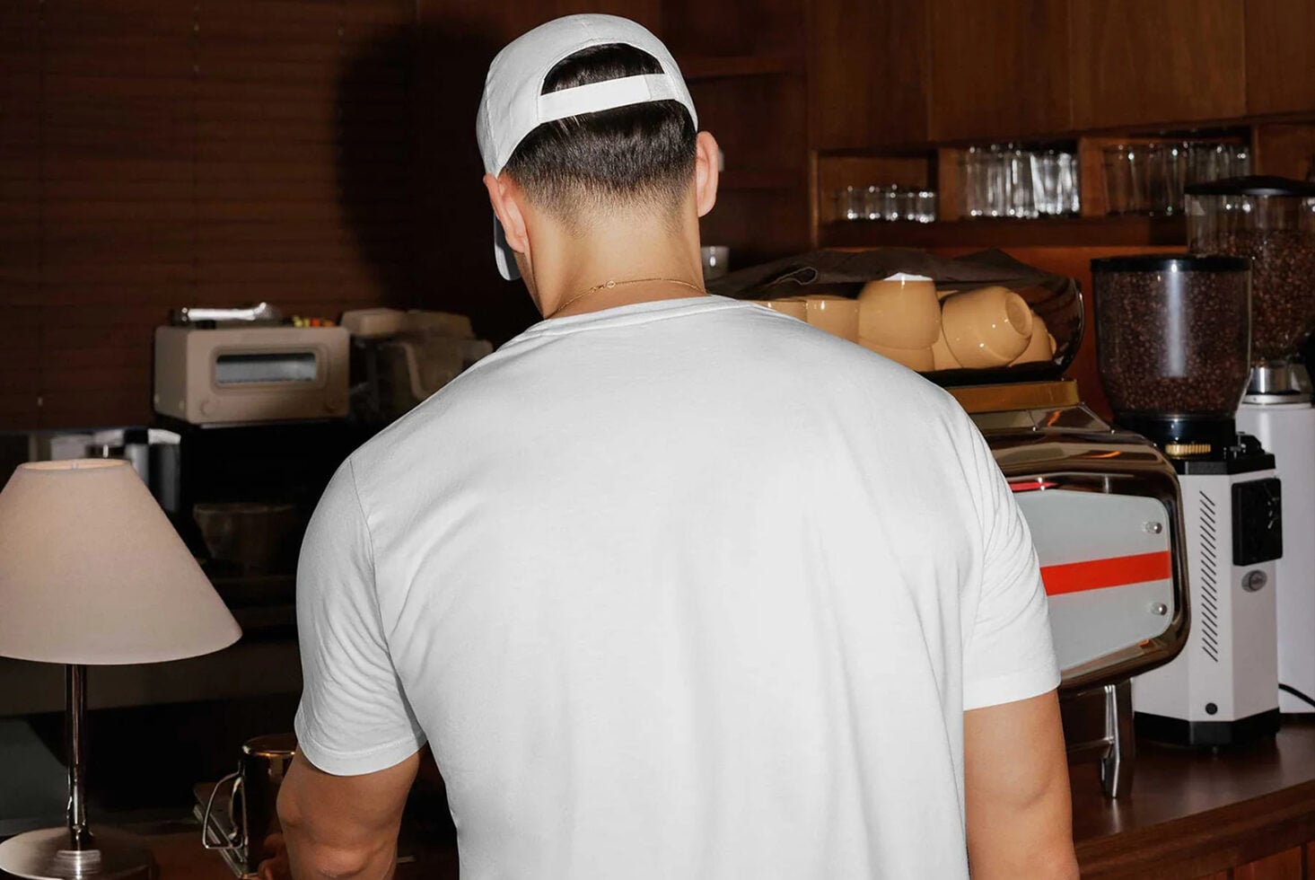 Guy in white cap looking at vintage tech setup with retro appliances on wooden desk