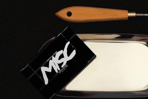 Wooden brush handle with metal ferrule next to black business card mockup with white script lettering