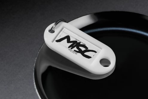 White keychain tag mockup with bold black brush lettering on dark background