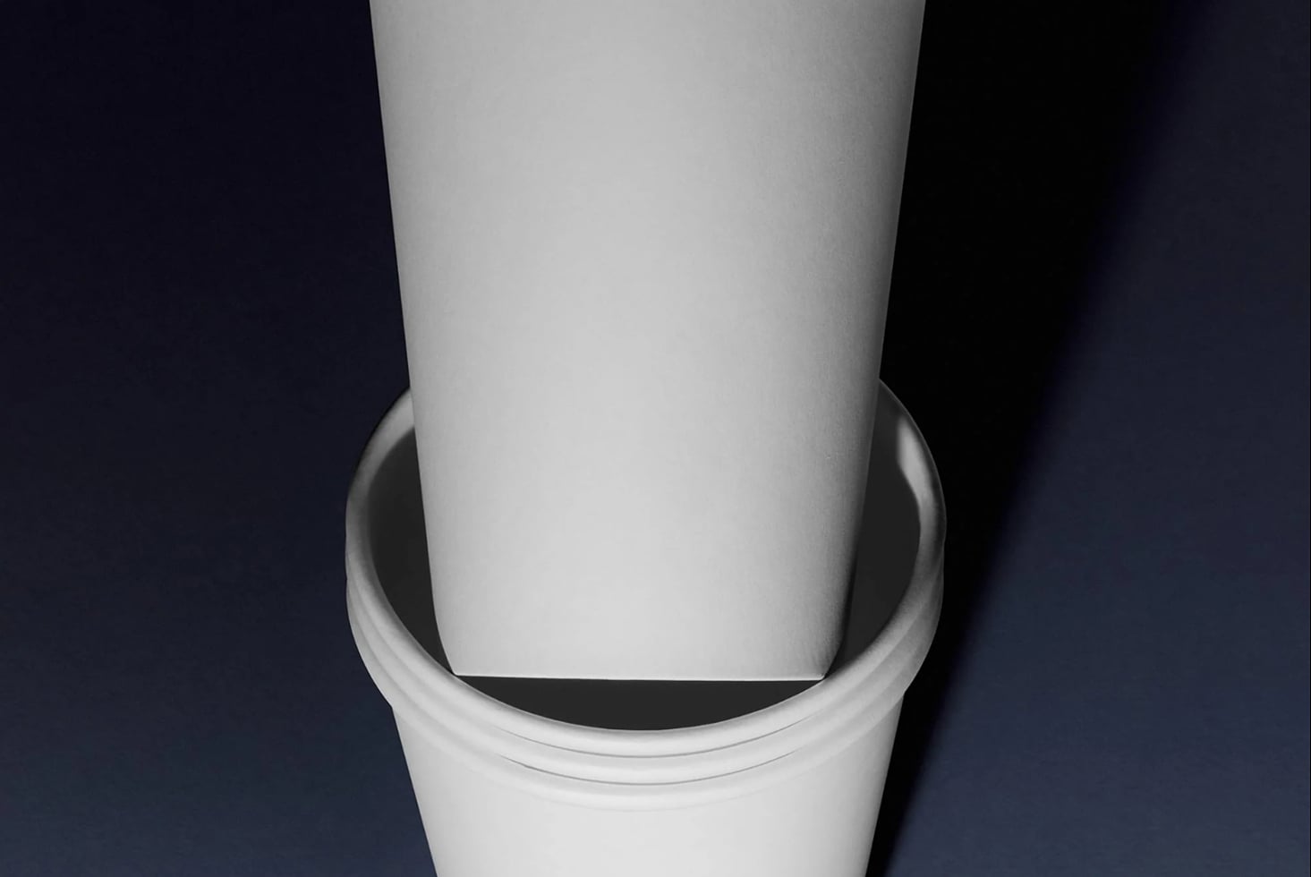Minimalist white cylinder mockup shot from above on dark navy background