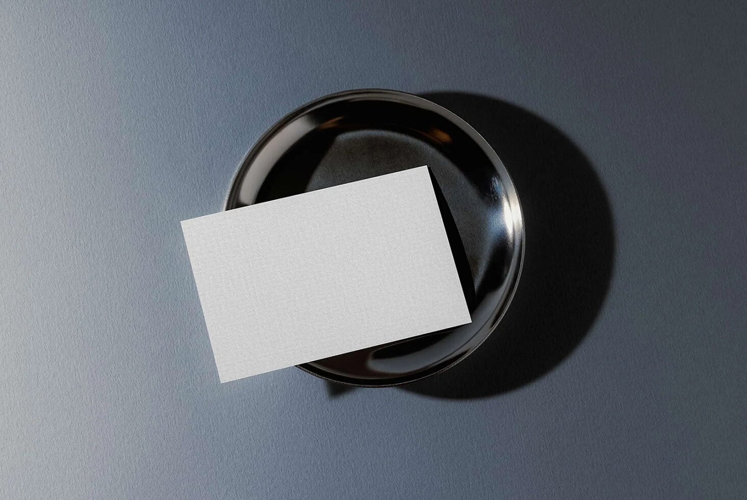Blank business card mockup draped over black ceramic bowl on slate background