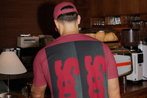 Back view of person wearing maroon cap with bold red graphic tee in kitchen setting