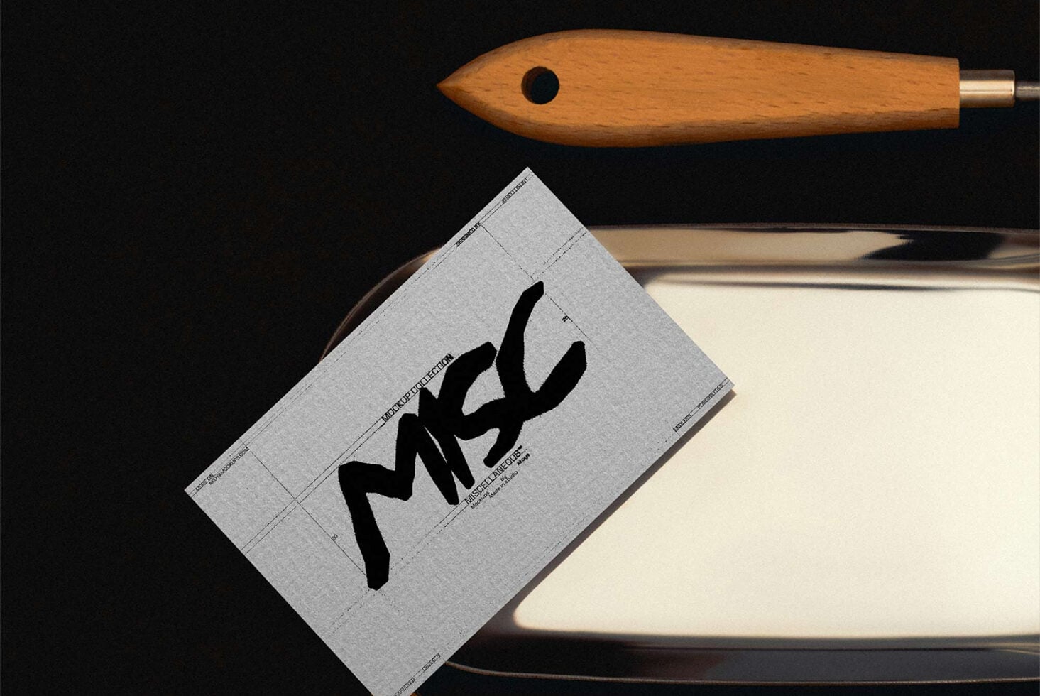 Sketchbook mockup with black ink stroke, wooden brush, brass pen on dark background