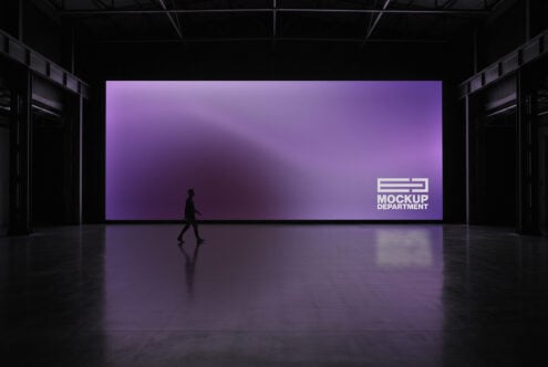 Large purple billboard display in dark warehouse space with silhouetted figure walking past