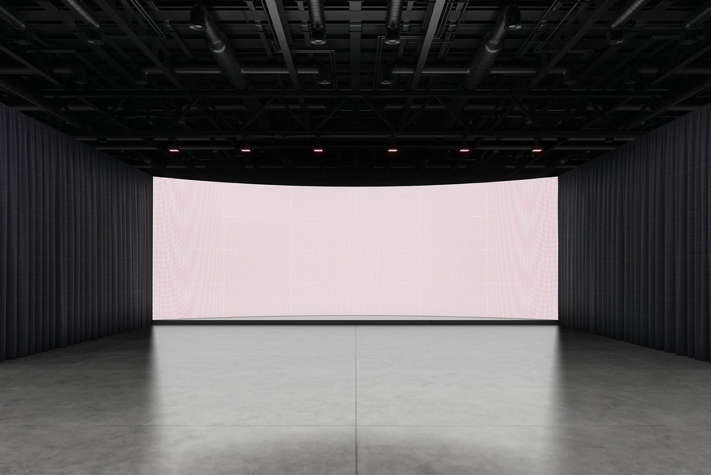 Large curved LED screen in dark industrial space with concrete floor