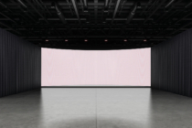 Large curved LED screen in dark industrial space with concrete floor