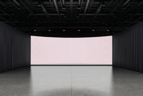 Large curved LED screen in dark industrial space with concrete floor