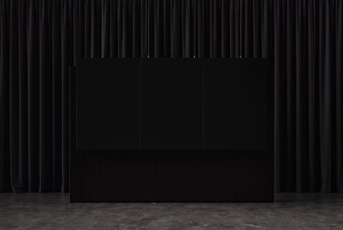 Three blank posters hanging on black curtain backdrop with concrete floor