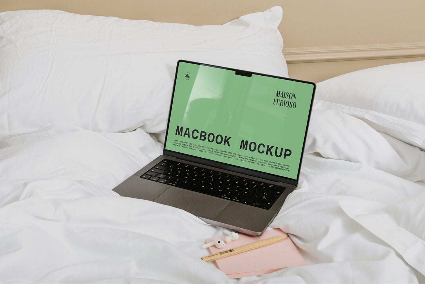 MacBook on white bedding with green screen displaying luxury brand mockup