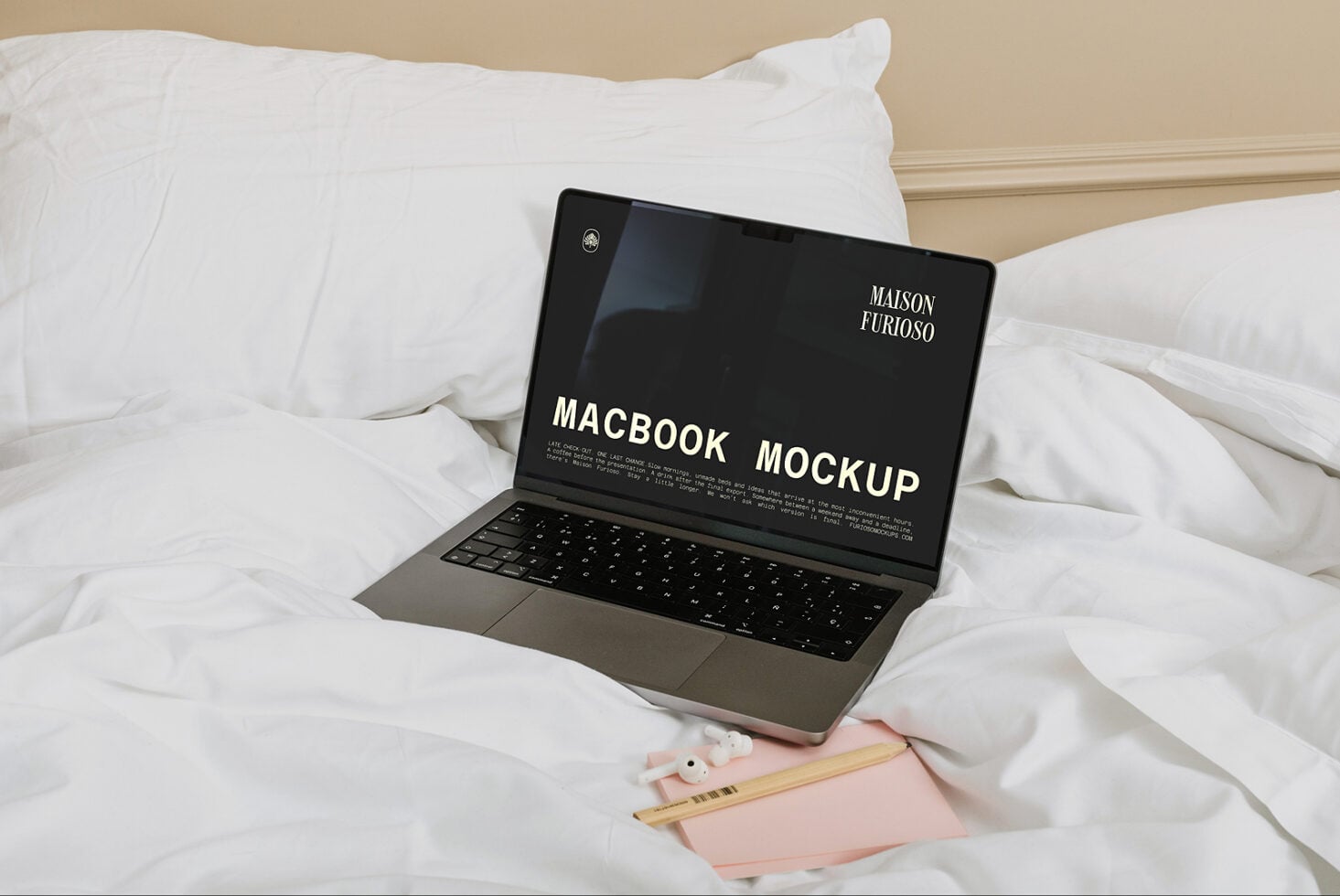 MacBook on white bedding with notebook, pencils, minimal aesthetic styling