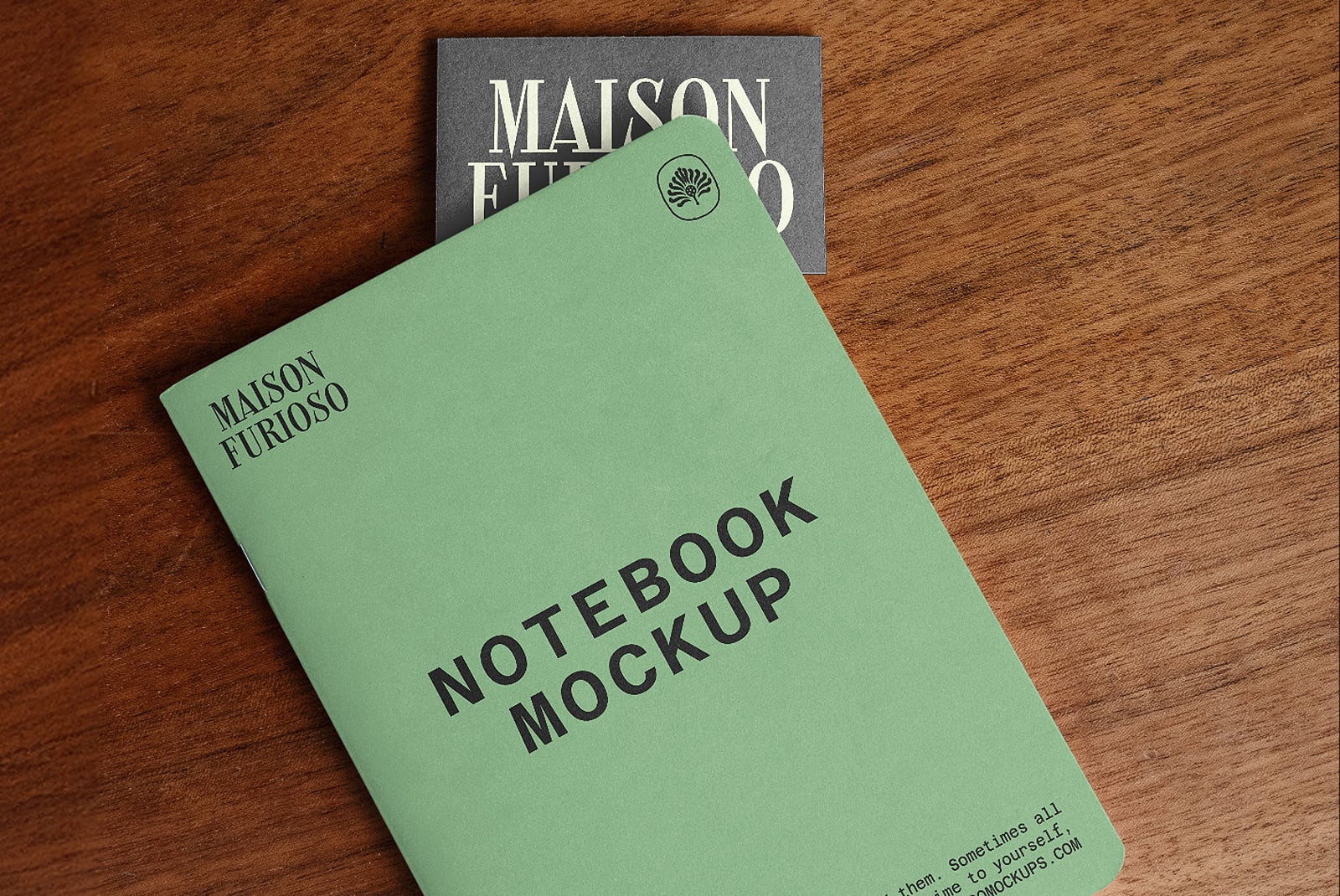 Sage green notebook mockup with brand tag, styled flat lay on wood with dark book behind