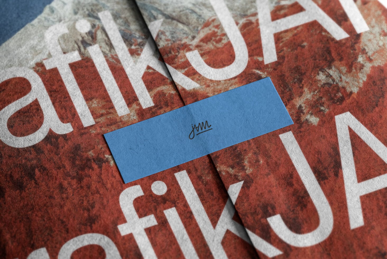 Blue business card with script logo sitting on distressed red fabric with white typography