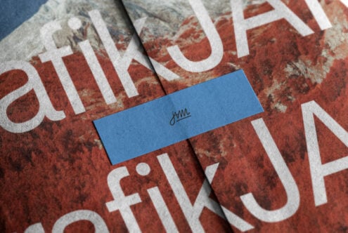Blue business card with script logo sitting on distressed red fabric with white typography