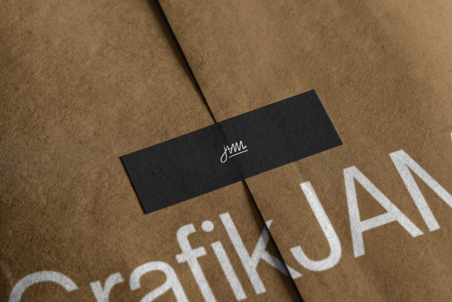 Black label with cursive logo on kraft paper with white stamped text below