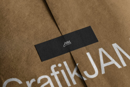 Black label with cursive logo on kraft paper with white stamped text below