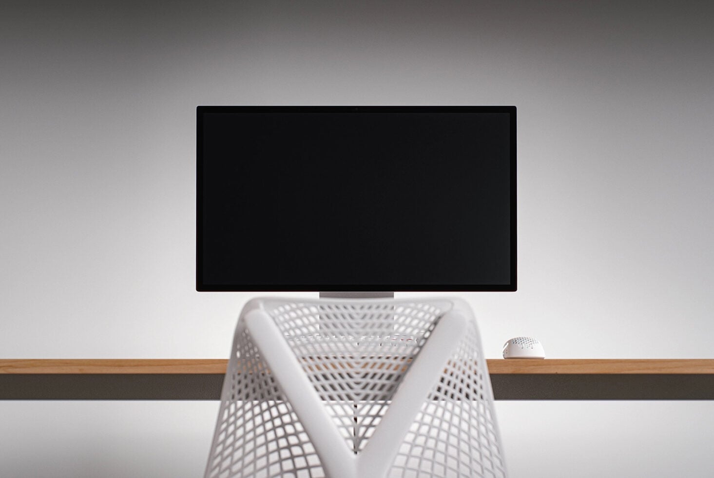Desktop monitor mockup with white mesh chair, wireless mouse on wooden desk