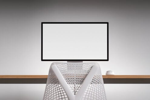 Monitor mockup with white mesh chair, wireless mouse on wooden desk