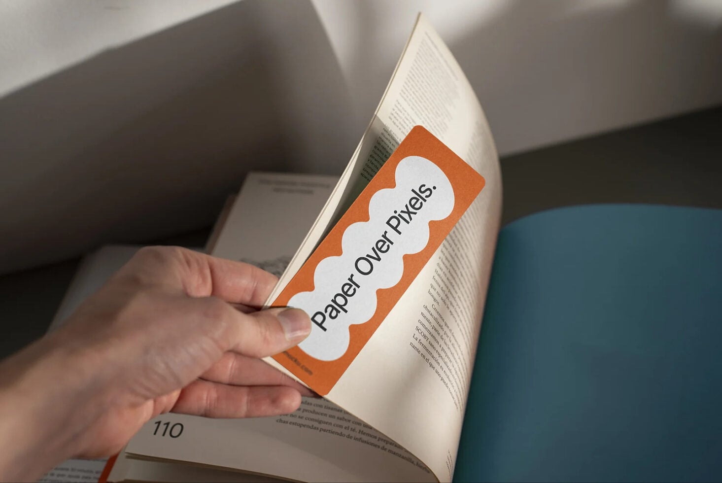 Paper over pixels bookmark mockup on open book in natural light