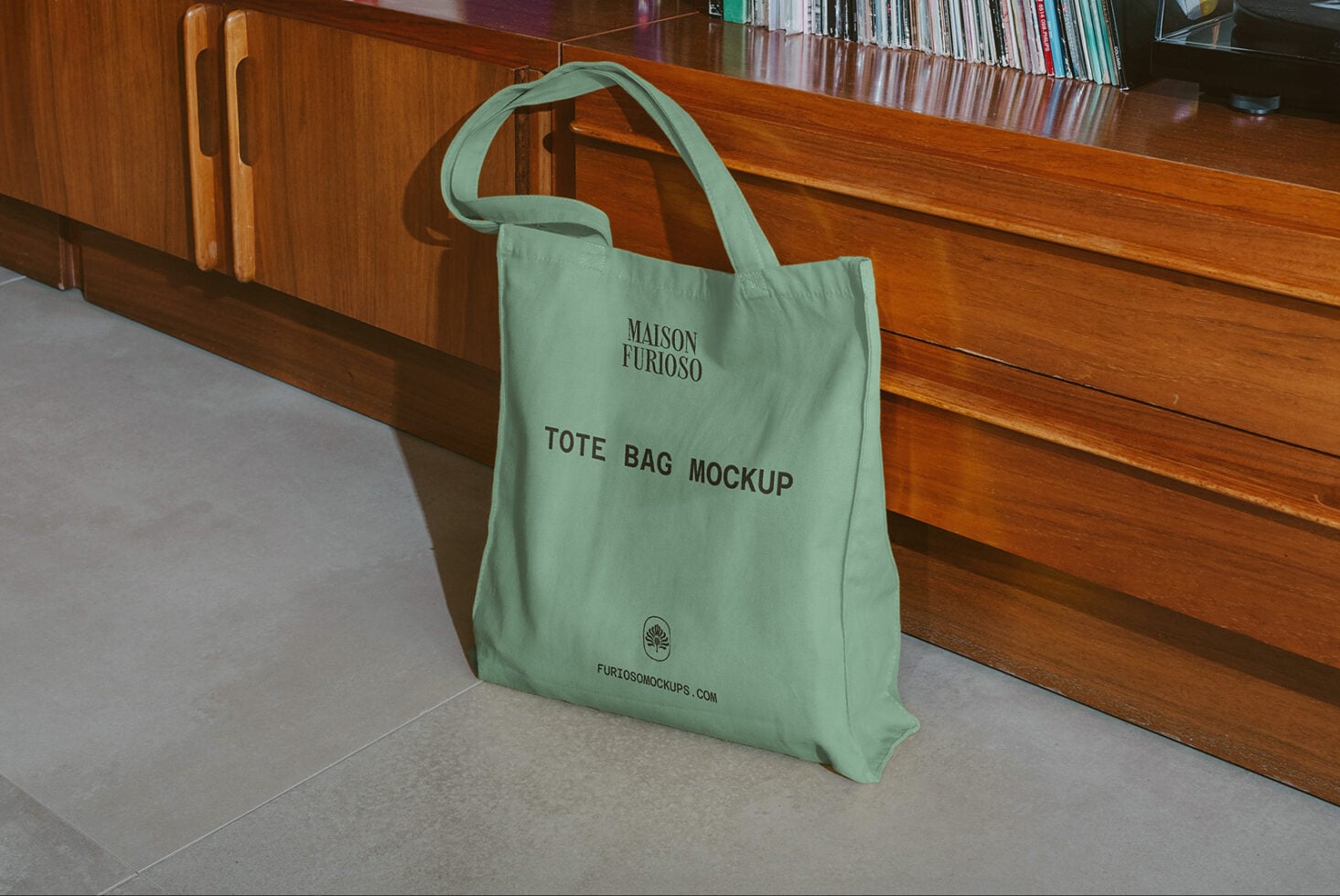 Mint green canvas tote bag sitting on concrete floor against wooden retail counter with books