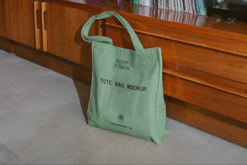 Mint green canvas tote bag sitting on concrete floor against wooden retail counter with books