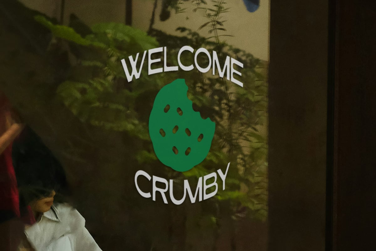 Welcome Crumby neon sign mockup with green leaf logo surrounded by plants