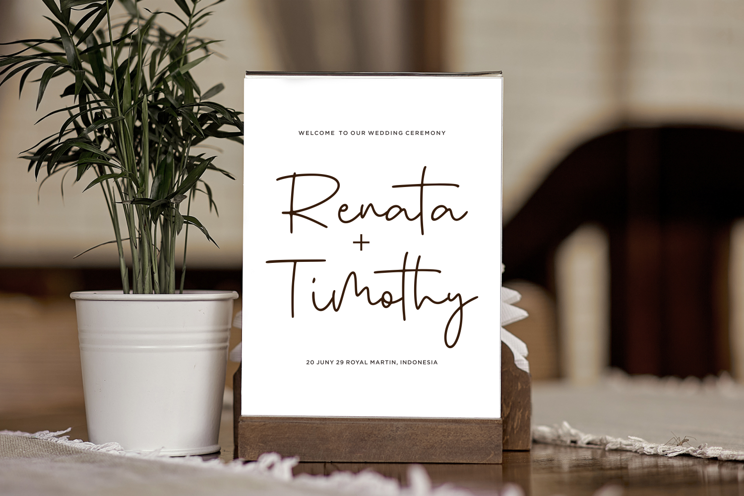 Wedding ceremony welcome sign mockup with handwritten names, potted plant, natural lighting