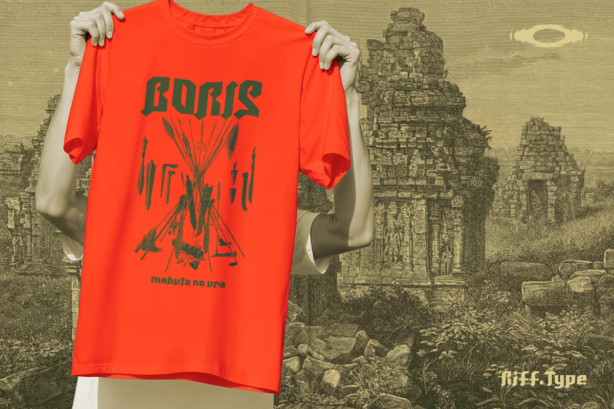 Bright red tee with dark green graphic design held up by mannequin against vintage temple backdrop