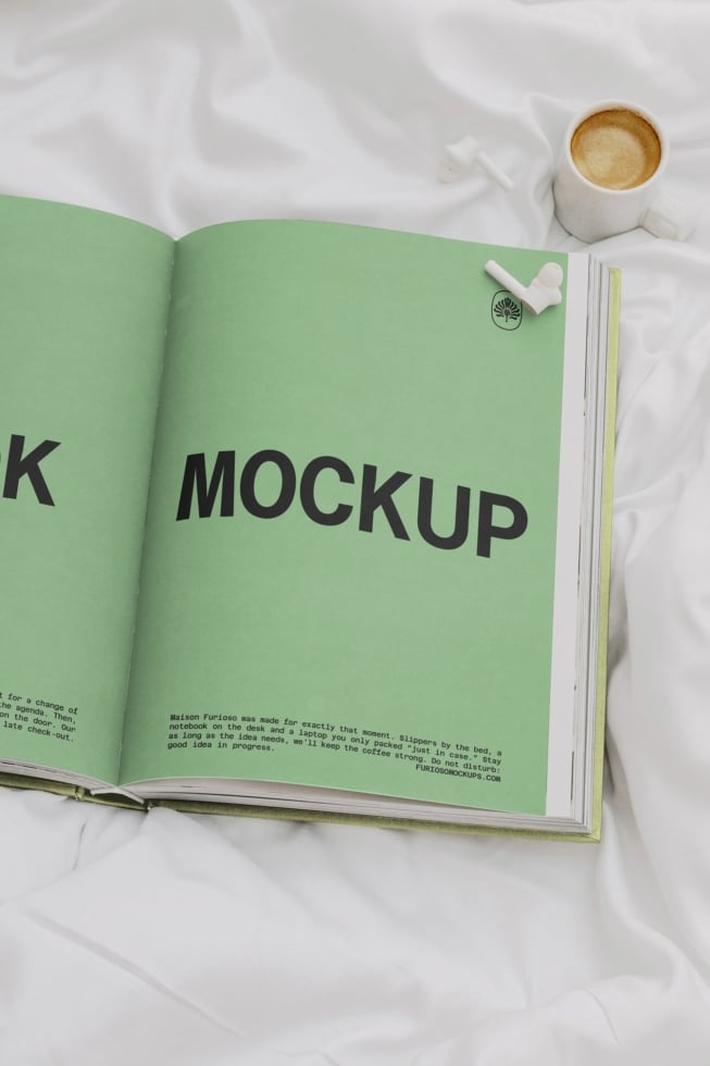 Open magazine spread on white fabric with coffee cup, plant pin, styling details