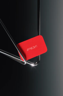 Bright red phone case mockup leaning against chrome stand on dark background