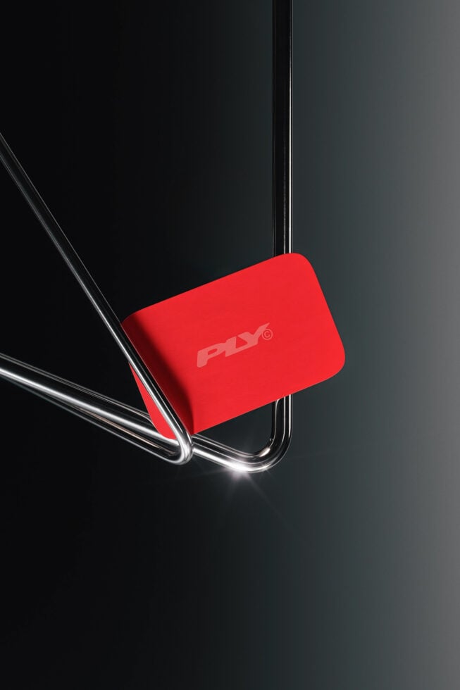 Bright red phone case mockup leaning against chrome stand on dark background