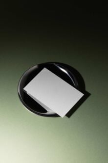 Blank business card mockup on black ceramic dish with sage green background
