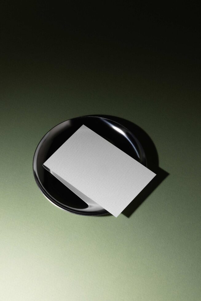 Blank business card mockup on black ceramic dish with sage green background