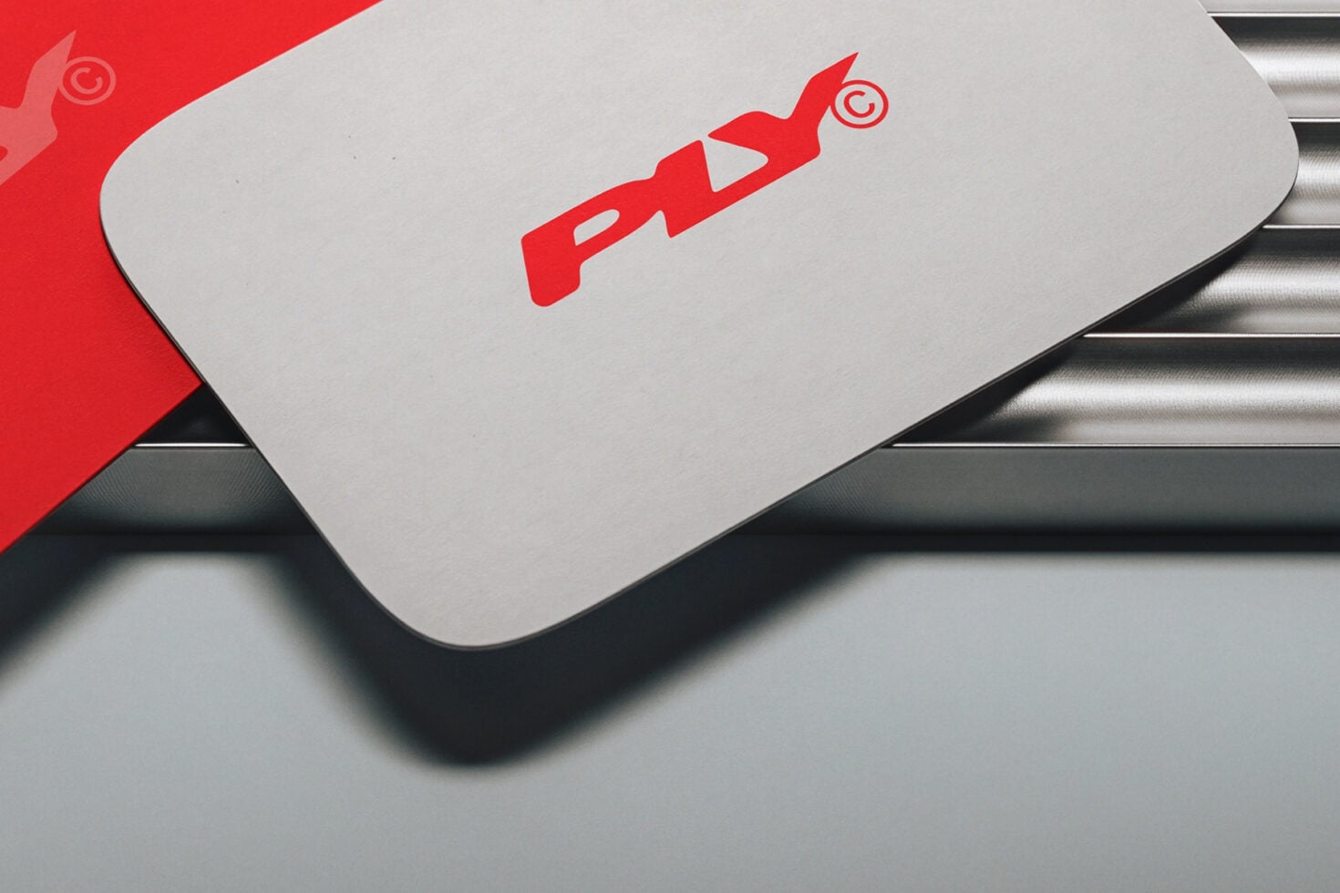Red rocket logo stamped on white rounded business card mockup with metallic accents