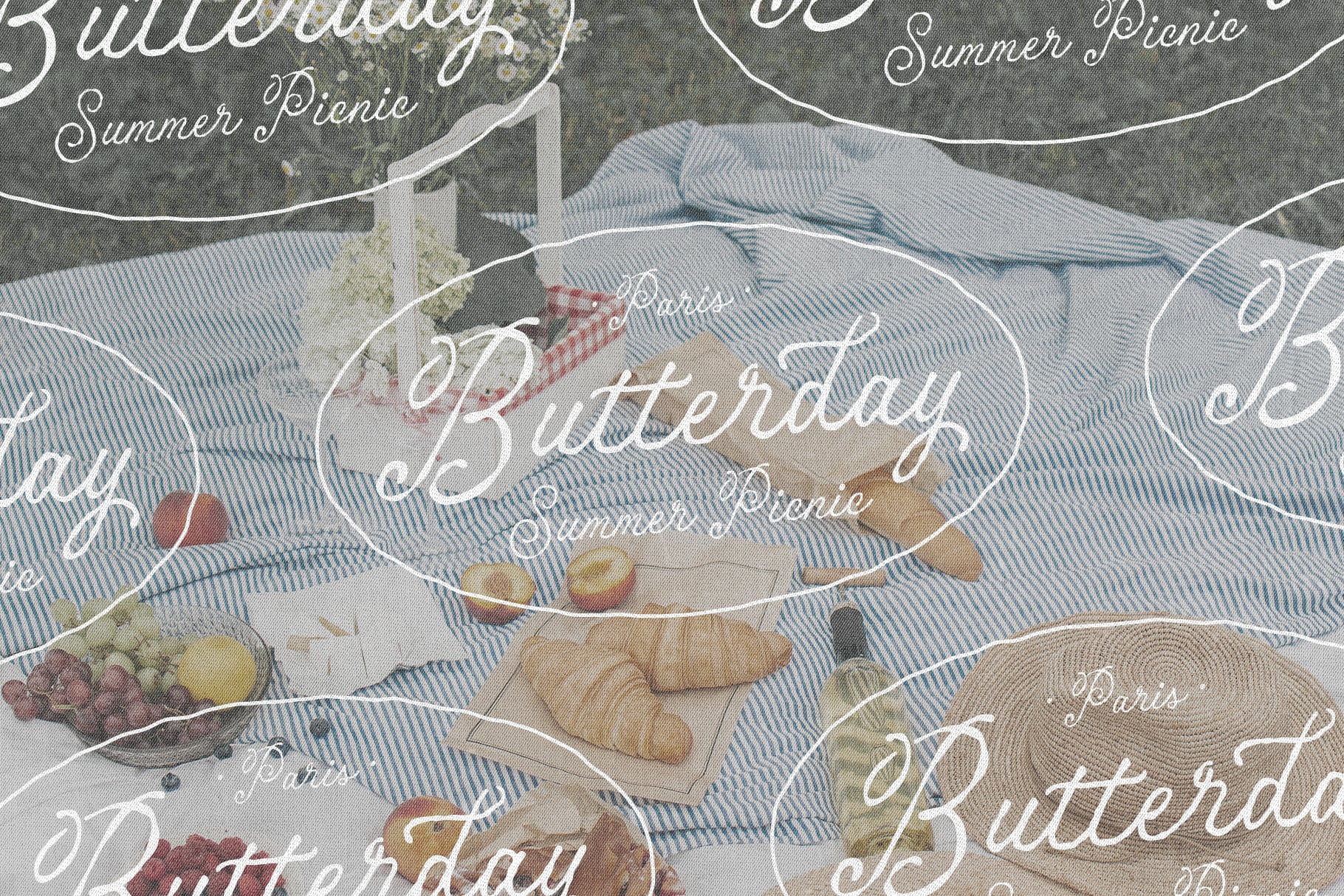 Overhead shot of picnic blanket spread with croissants, fruit, grapes on blue striped fabric