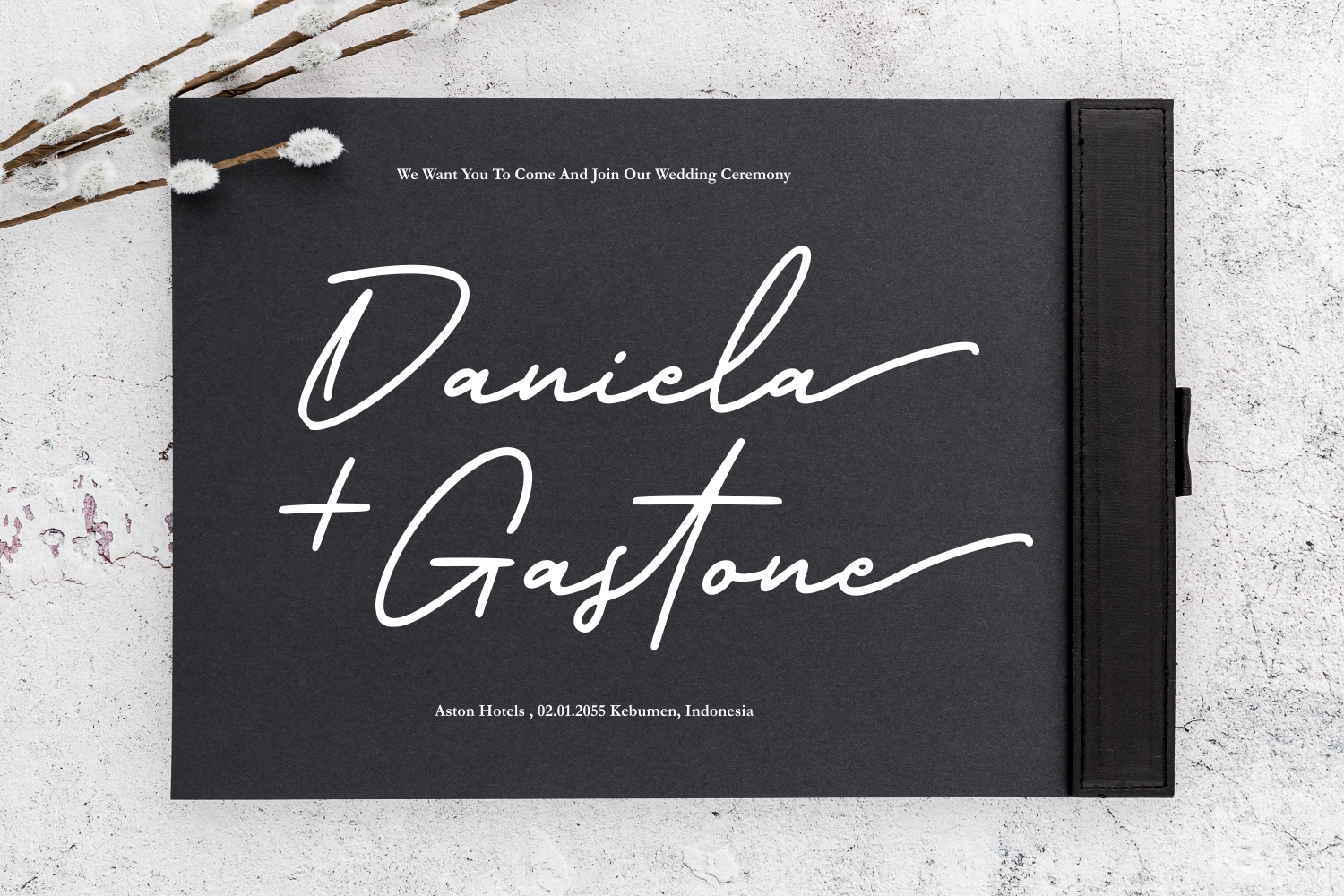 Black wedding invitation mockup with flowing script names, pampas grass, concrete backdrop