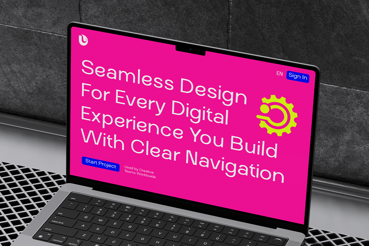 Laptop screen showing bright pink website hero with white sans-serif text, blue buttons, yellow gear icon