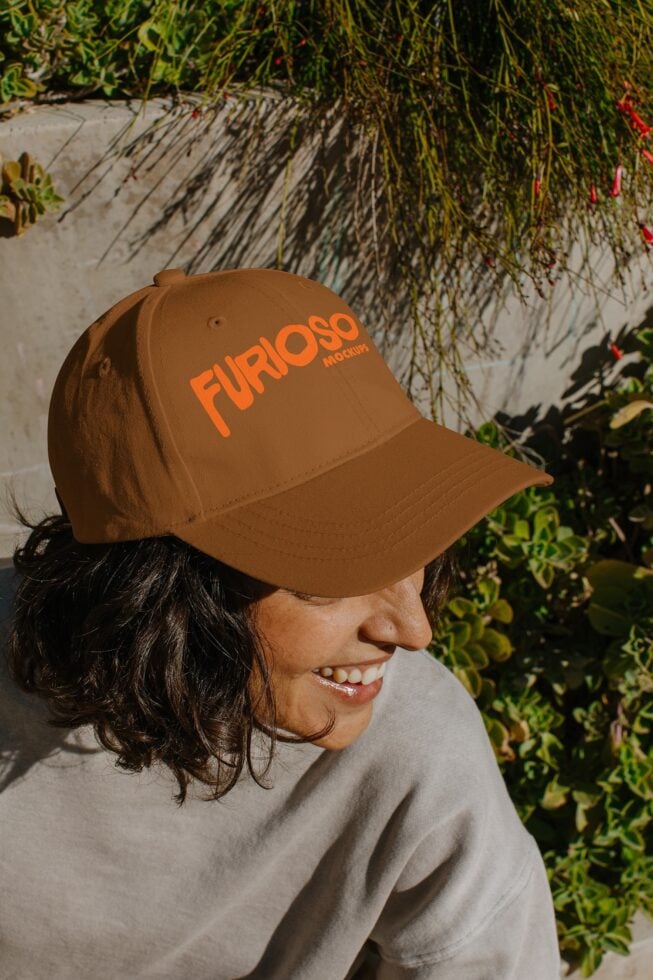 Tan baseball cap with orange FURIOSO text on model's head outdoors with ivy vines behind