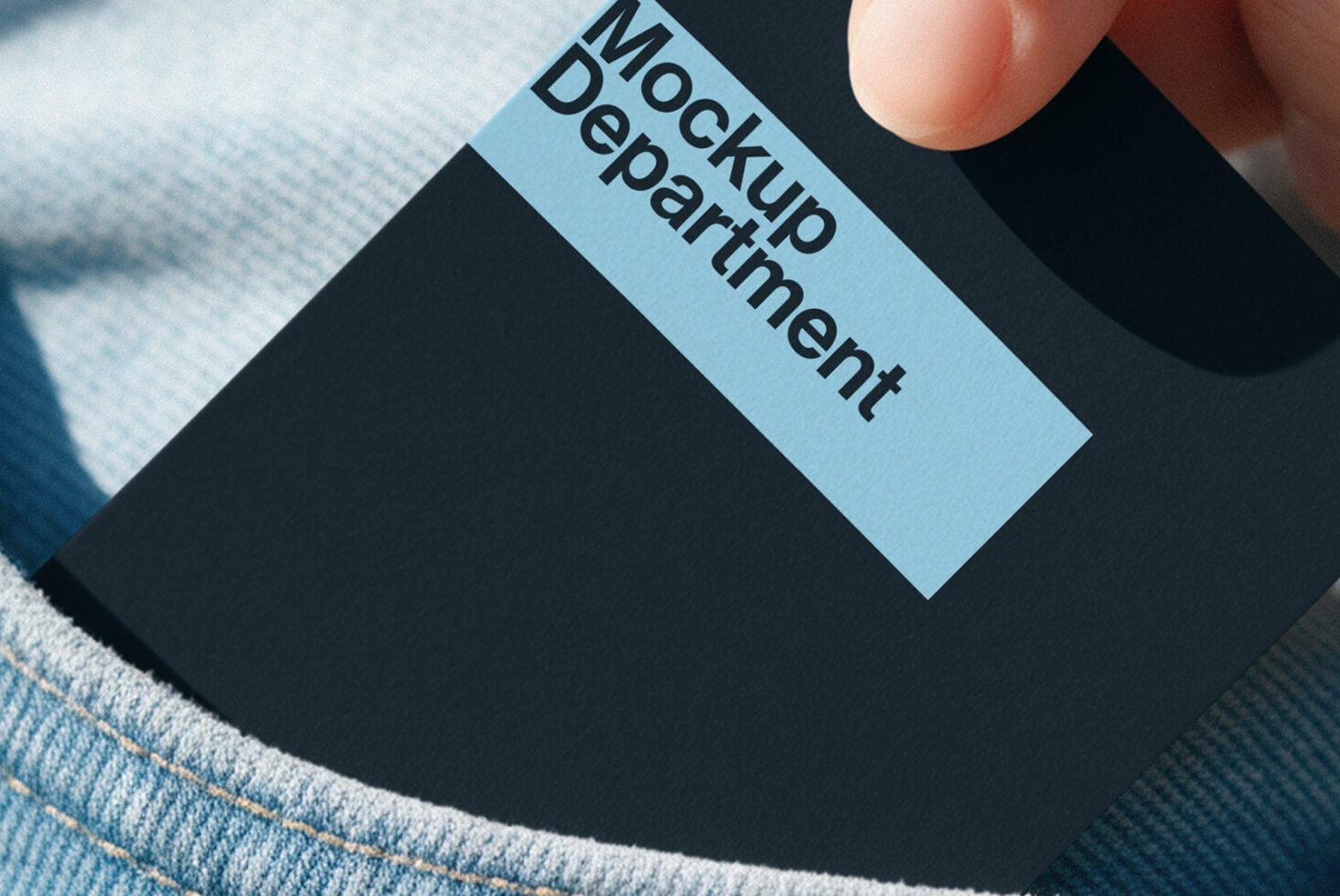 Hand holding light blue label with "Mockup Department" text on dark box over fabric background