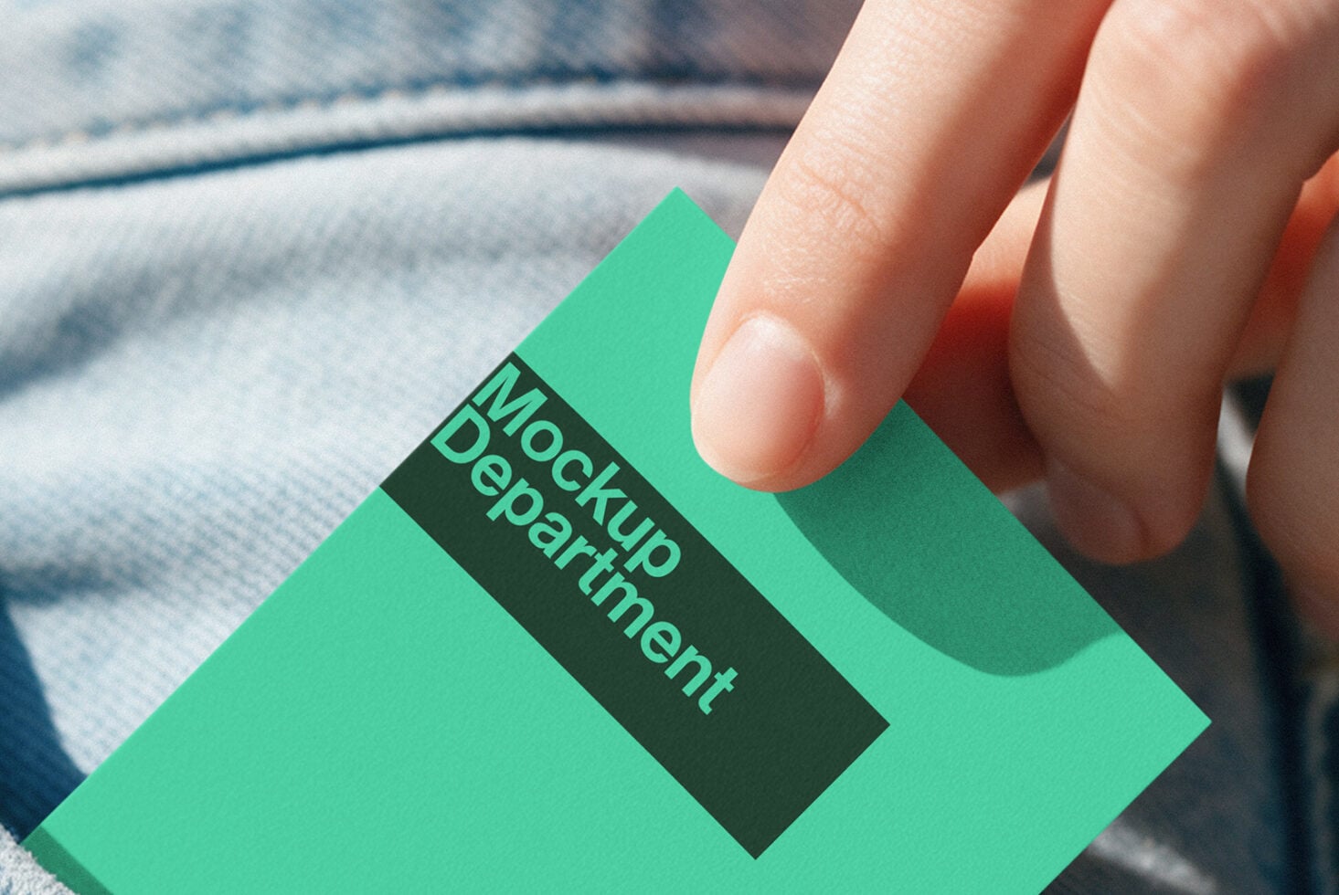 Hand holding bright mint green business card with dark label on fabric texture background