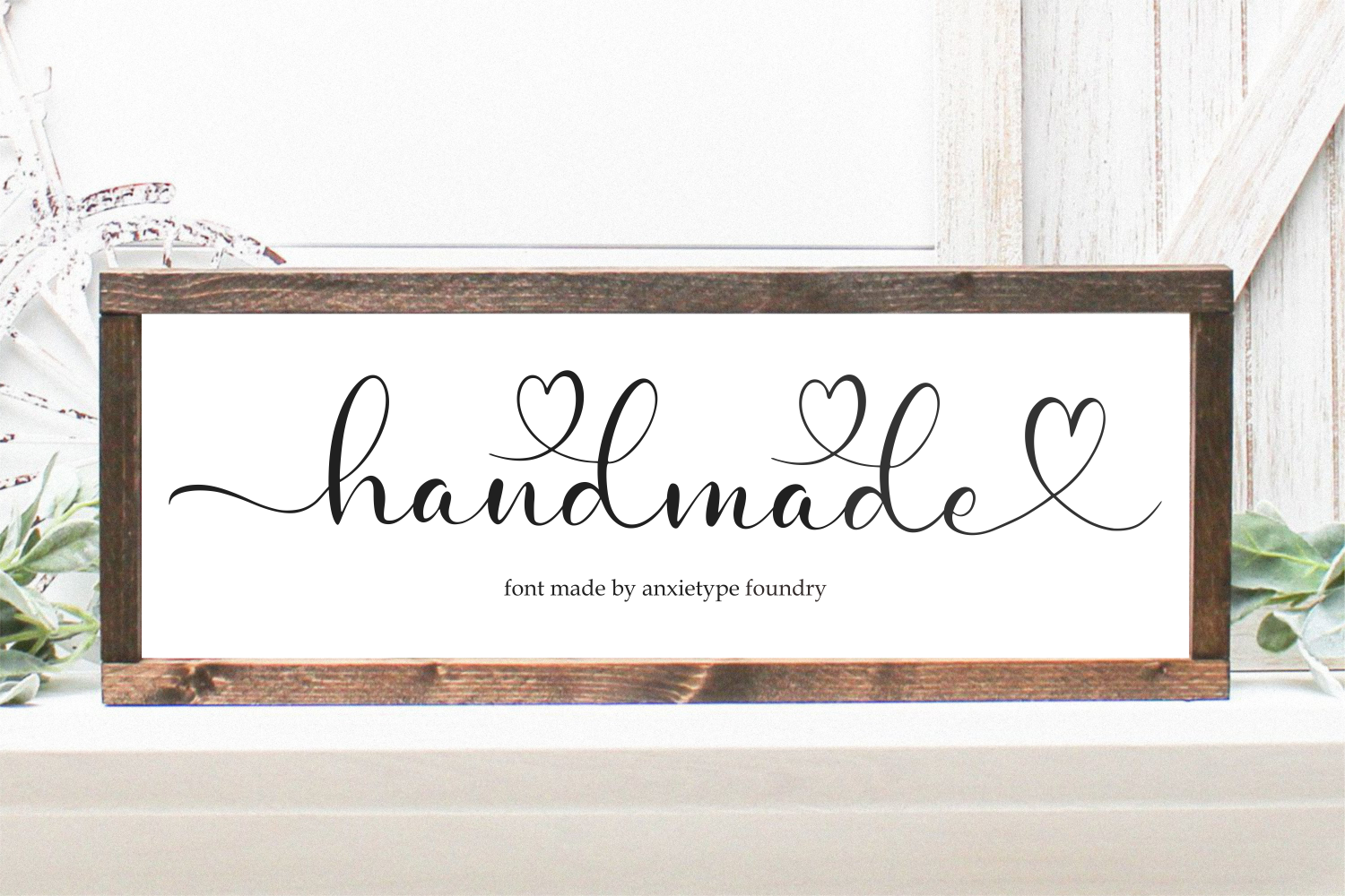 Framed print showing "handmade" in flowing script with heart details, rustic wood frame