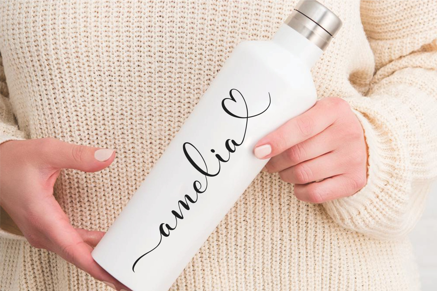White water bottle with script text held in hands over cream knit fabric