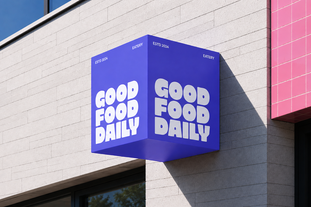 Bold blue cube storefront sign with white "Good Food Daily" text on modern brick building facade