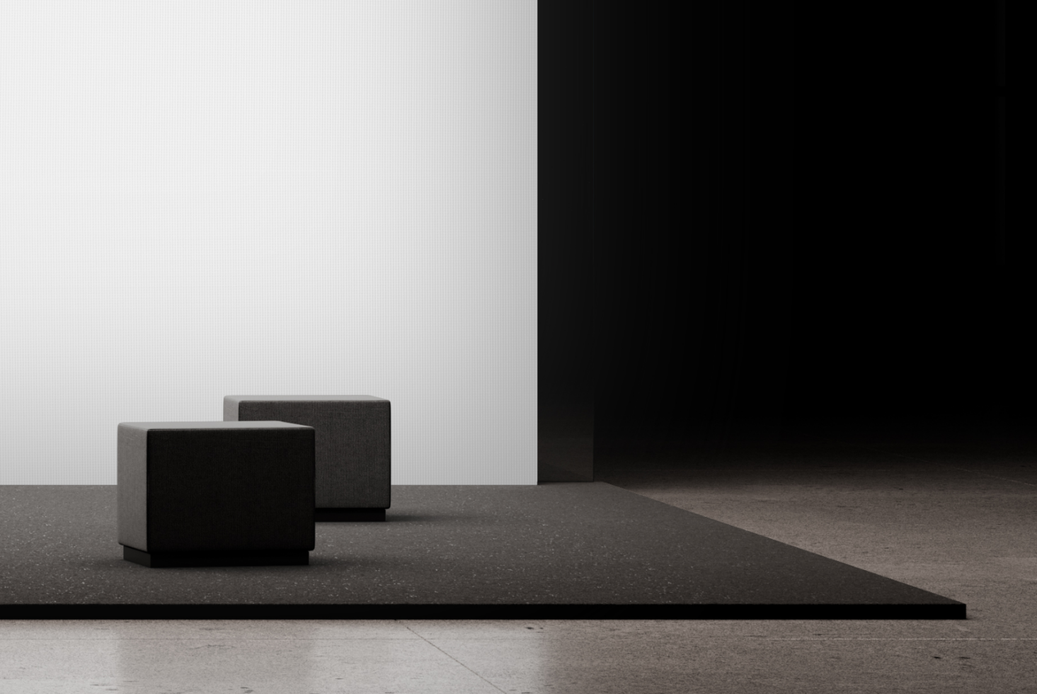 Minimal product display with two dark fabric poufs on concrete platform against white wall