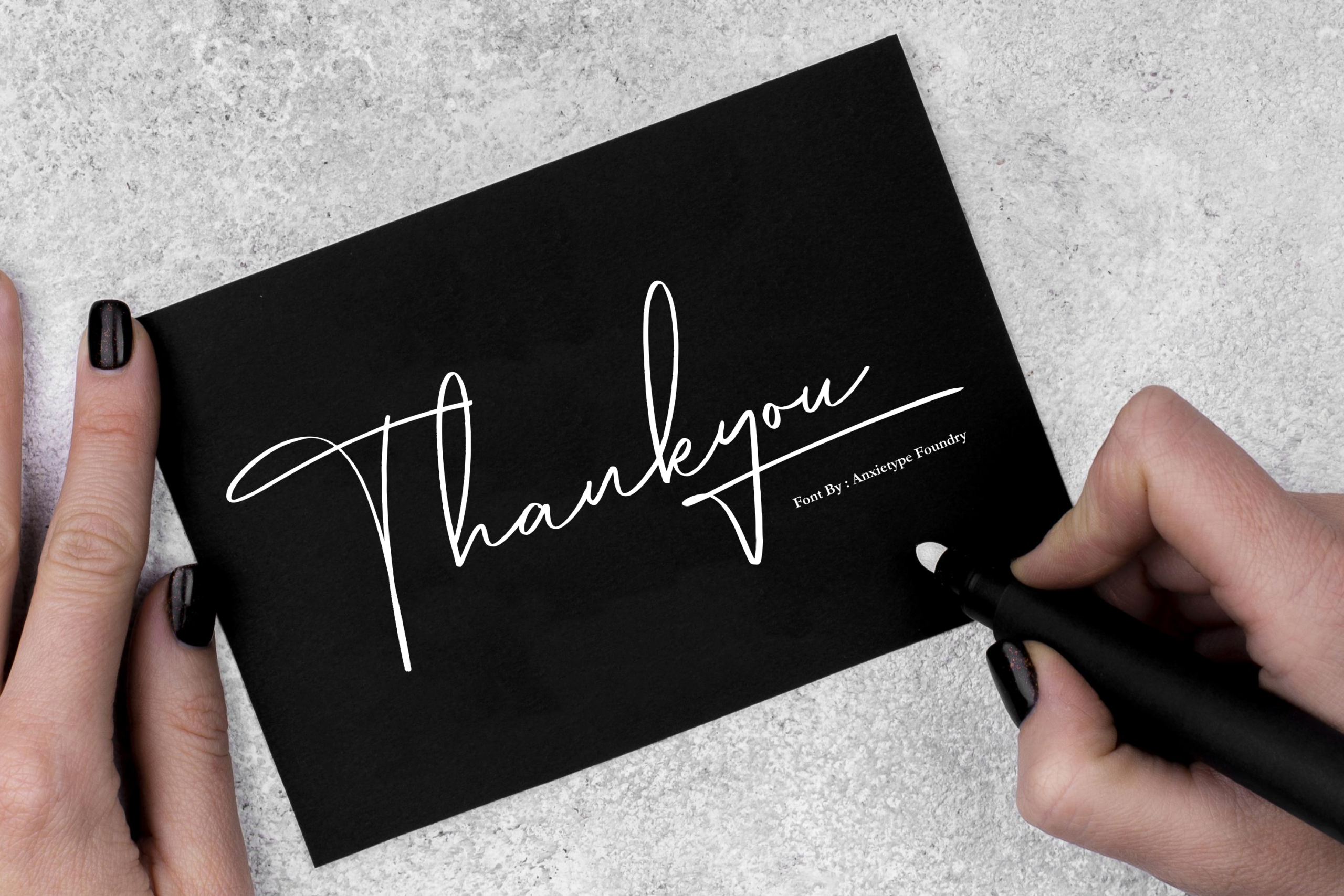 Hands holding black card with elegant white script thankyou text on concrete background