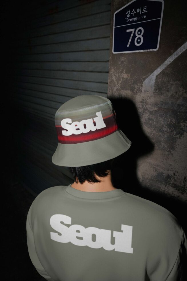 Person wearing Seoul bucket hat with matching sweatshirt in gritty urban setting