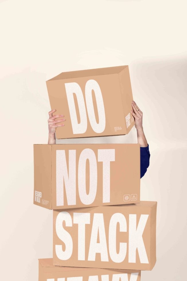 Person holding stacked cardboard boxes reading "Do Not Stack" in bold white letters