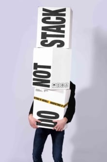 Stacked shipping boxes mockup with bold black typography, person holding them with head covered